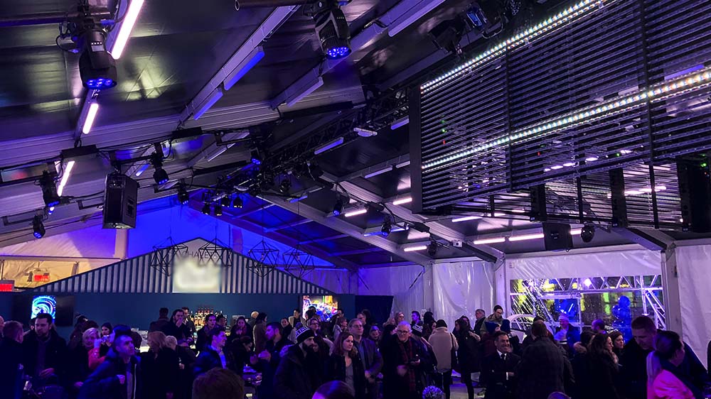 Packed concert crowd inside clearspan structure tent with professional stage lighting, LED bars, and aluminum frame roof