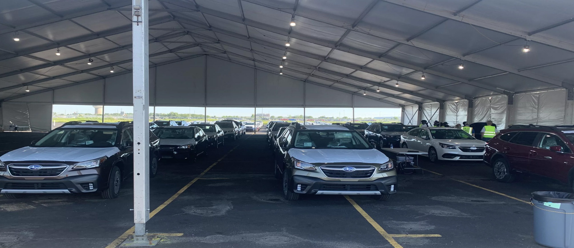 Temporary vehicle storage tent protecting automotive fleet with drive-through clearspan access