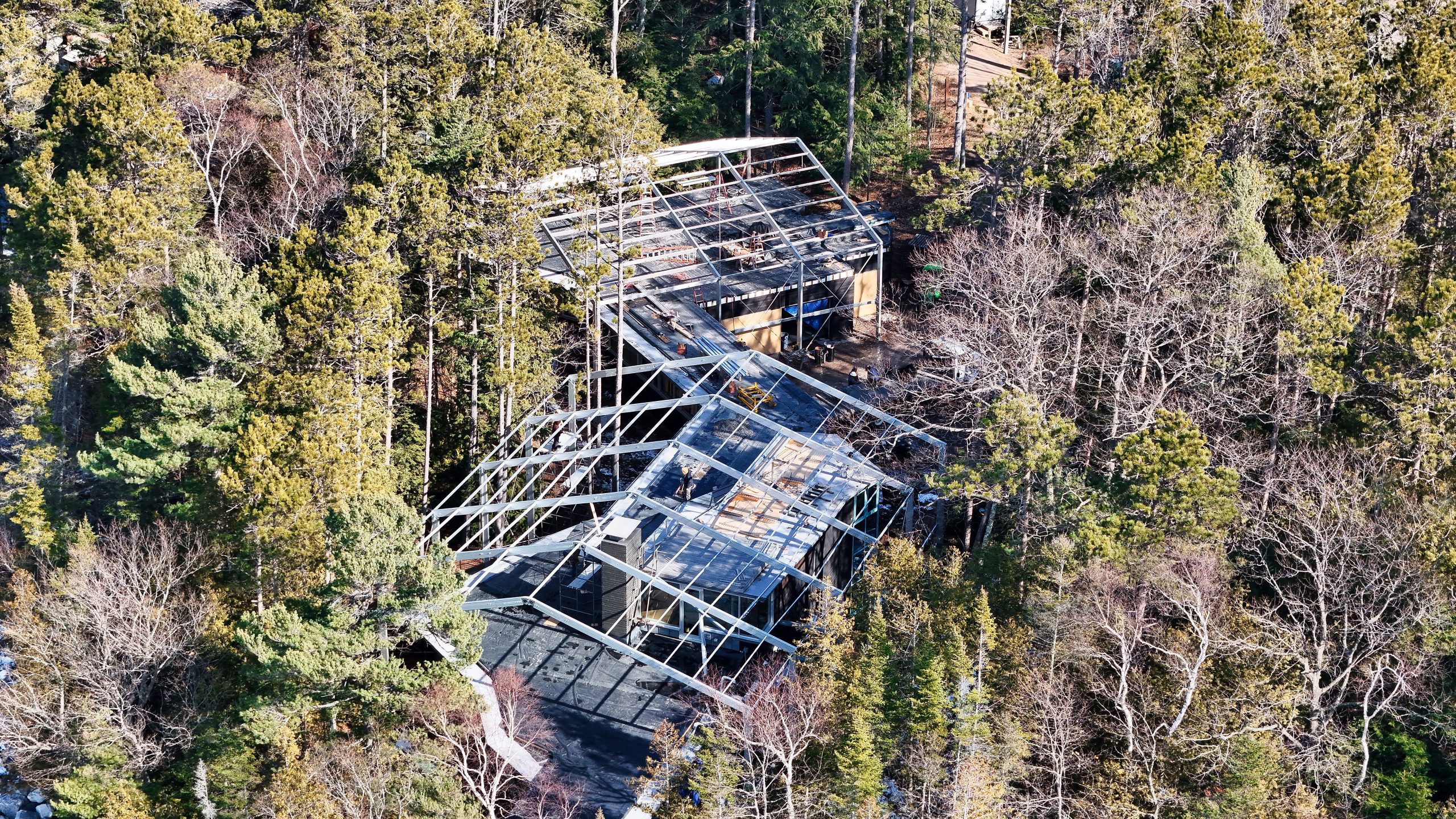 Aerial view of building restoration tent structure over residential building in wooded setting with exposed aluminum frame