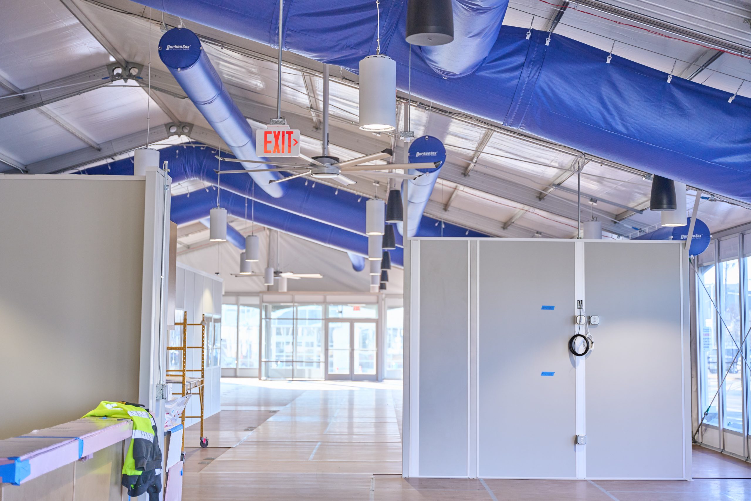 Interior of temporary office structure with blue HVAC ducting, modular wall partitions, pendant lighting, and commercial ceiling systems