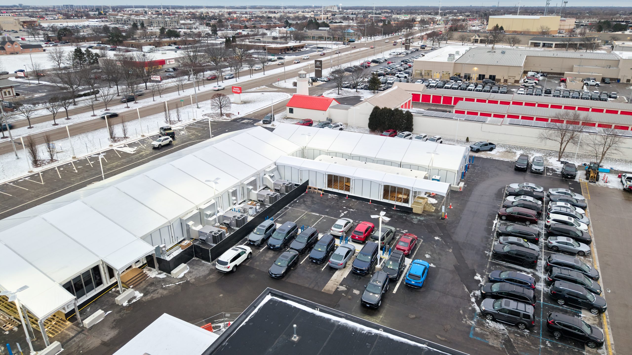 Aerial view of temporary office building complex in commercial parking lot with glass walls, white fabric structure, and connected sections